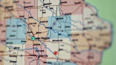 Close-up of a map highlighting parts of eastern Iowa, with Cedar Rapids and Iowa City marked by coloured pins. City names, county lines, and major roads are clearly visible.